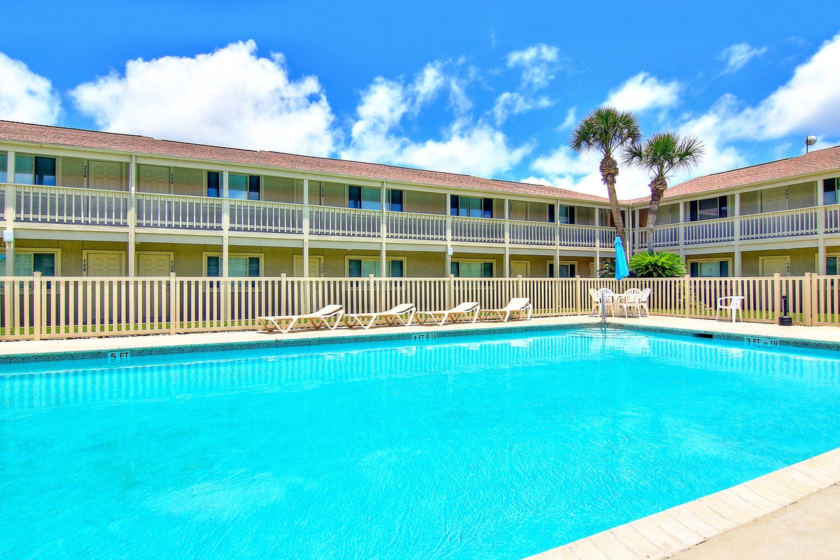 A sparkling swimming pool surrounded by two-story buildings with balconies creates the perfect tropical courtyard retreat.