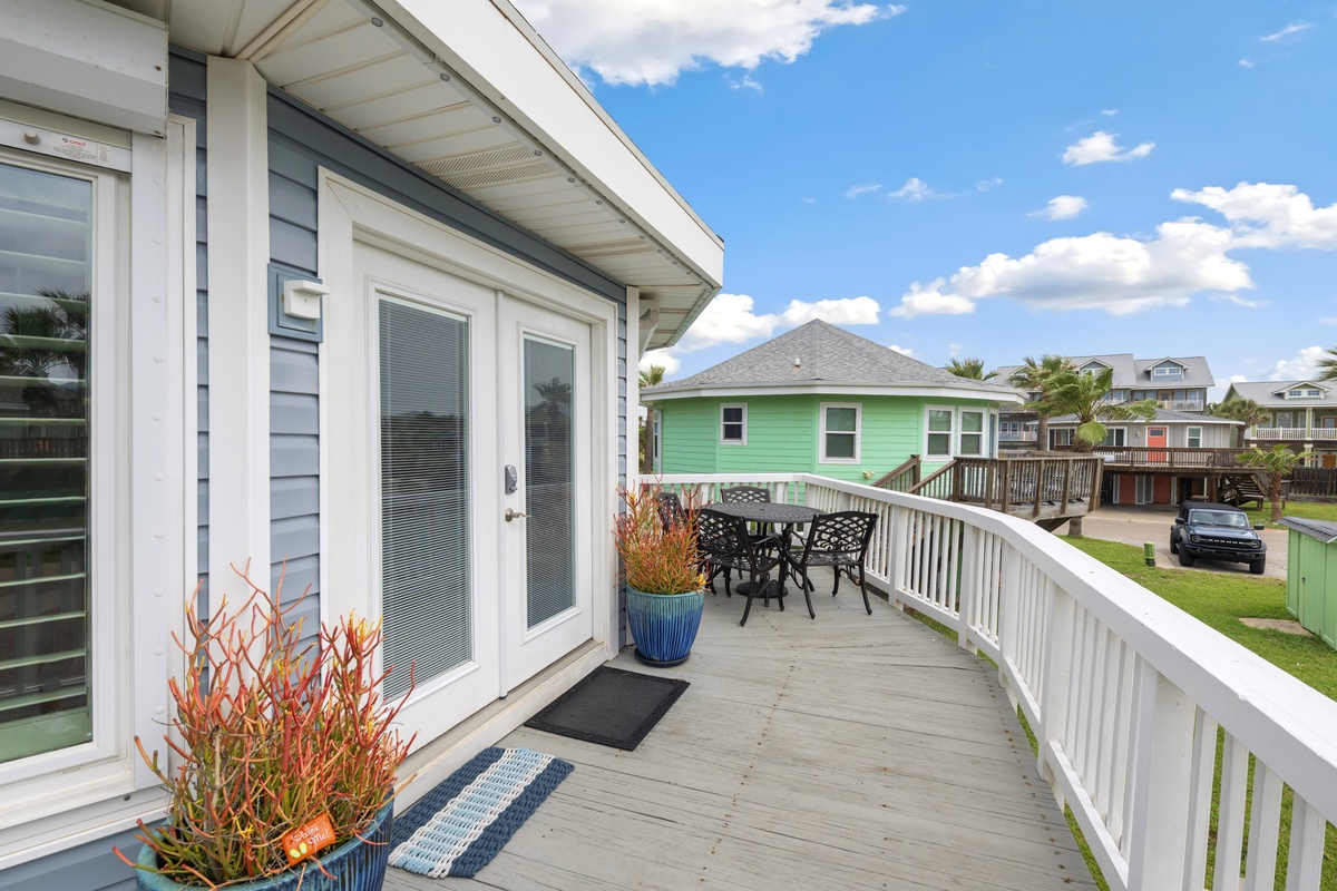 Step onto your private deck with outdoor dining and neighborhood views under bright coastal skies.