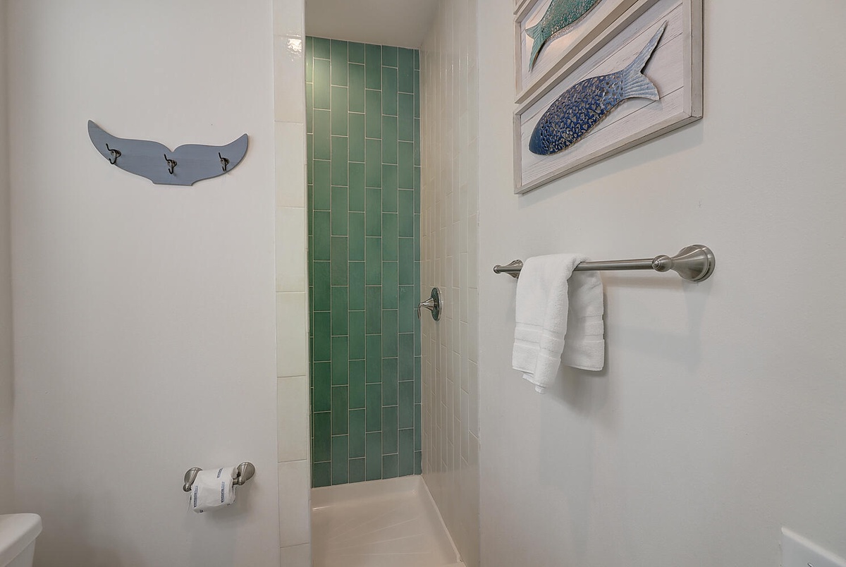 Step into your coastal-themed bathroom with soothing sea glass tiles and fresh towels waiting for you.