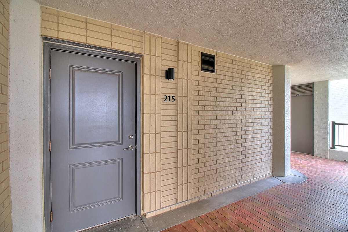 Exterior entrance of unit 215 with covered walkway and brick flooring leading to your private door.