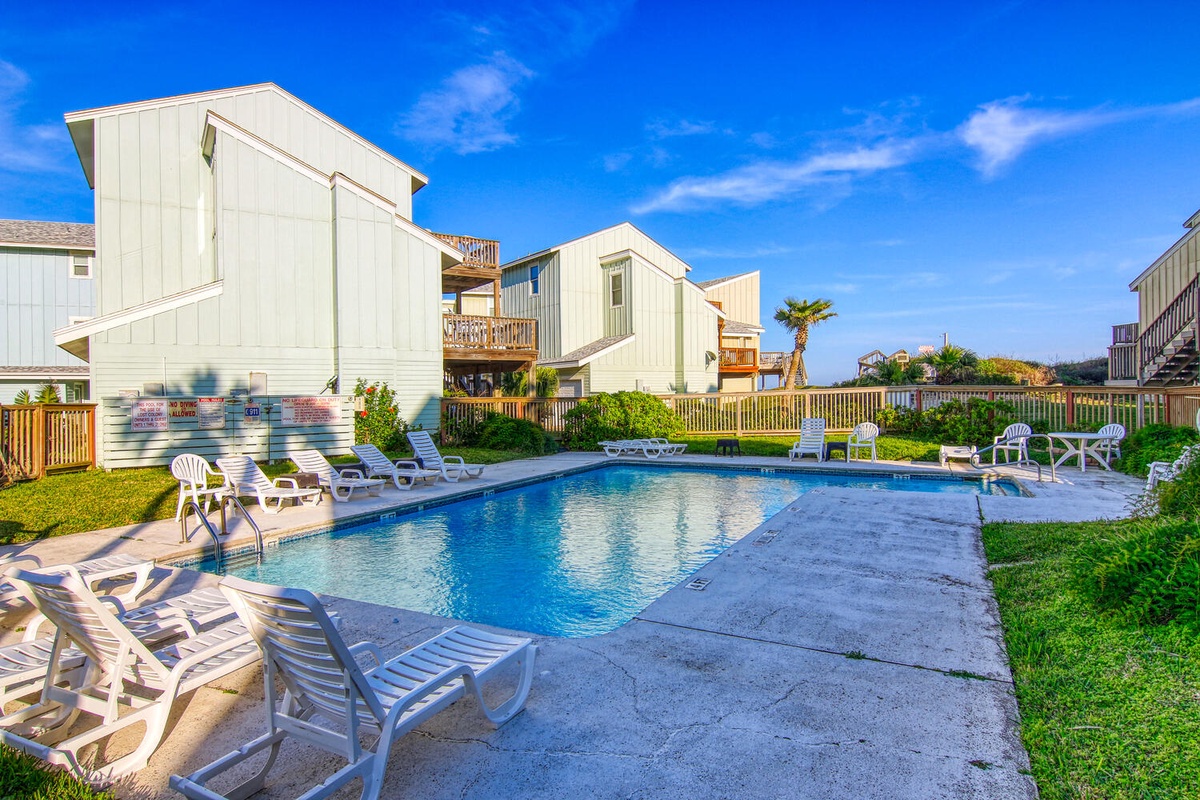Dive into your private oasis with sparkling pool waters surrounded by lush green lawn and comfortable lounge chairs.