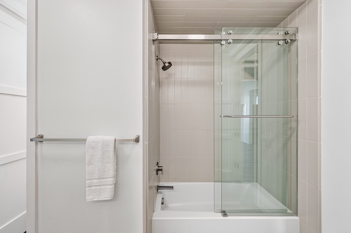 Step into the guest bathroom offering a tub/shower combo with fresh towels and modern fixtures.