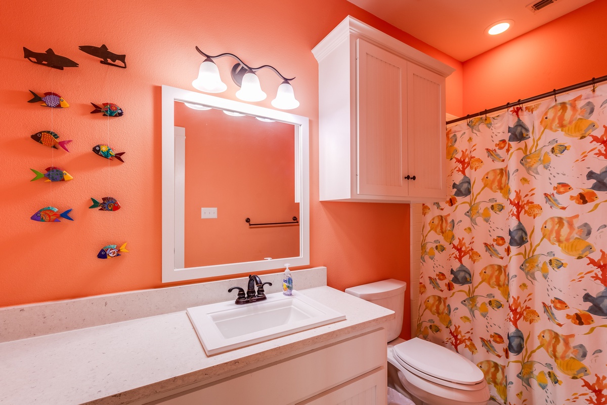 Dive into this vibrant coral bathroom where tropical fish swim along your walls and ocean-themed décor transforms your daily routine into an underwater adventure.