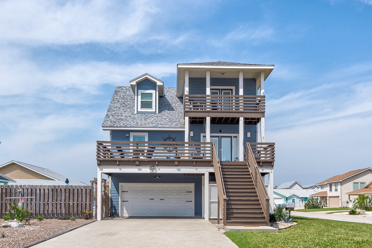 A modern three-story coastal home featuring multiple balconies and elevated design in a peaceful neighborhood.