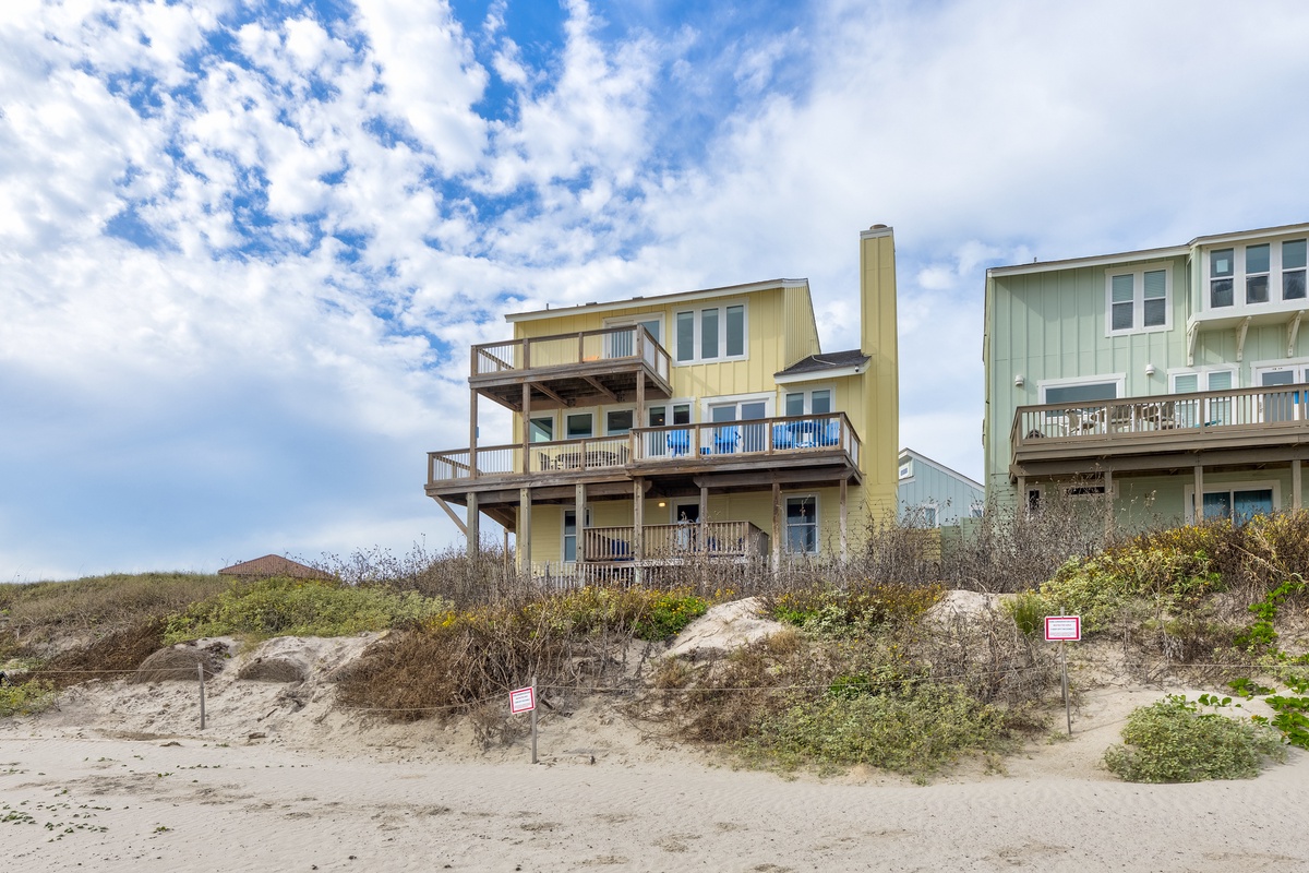 Beachfront property with multiple decks overlooking the shoreline, featuring natural dune vegetation and coastal architecture.