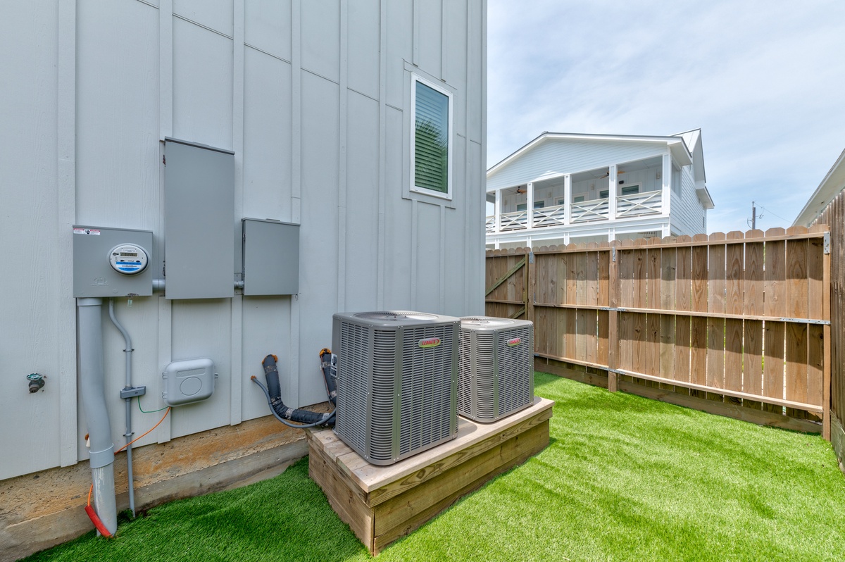 Modern property featuring dual air conditioning units and well-maintained outdoor space with artificial turf landscaping.