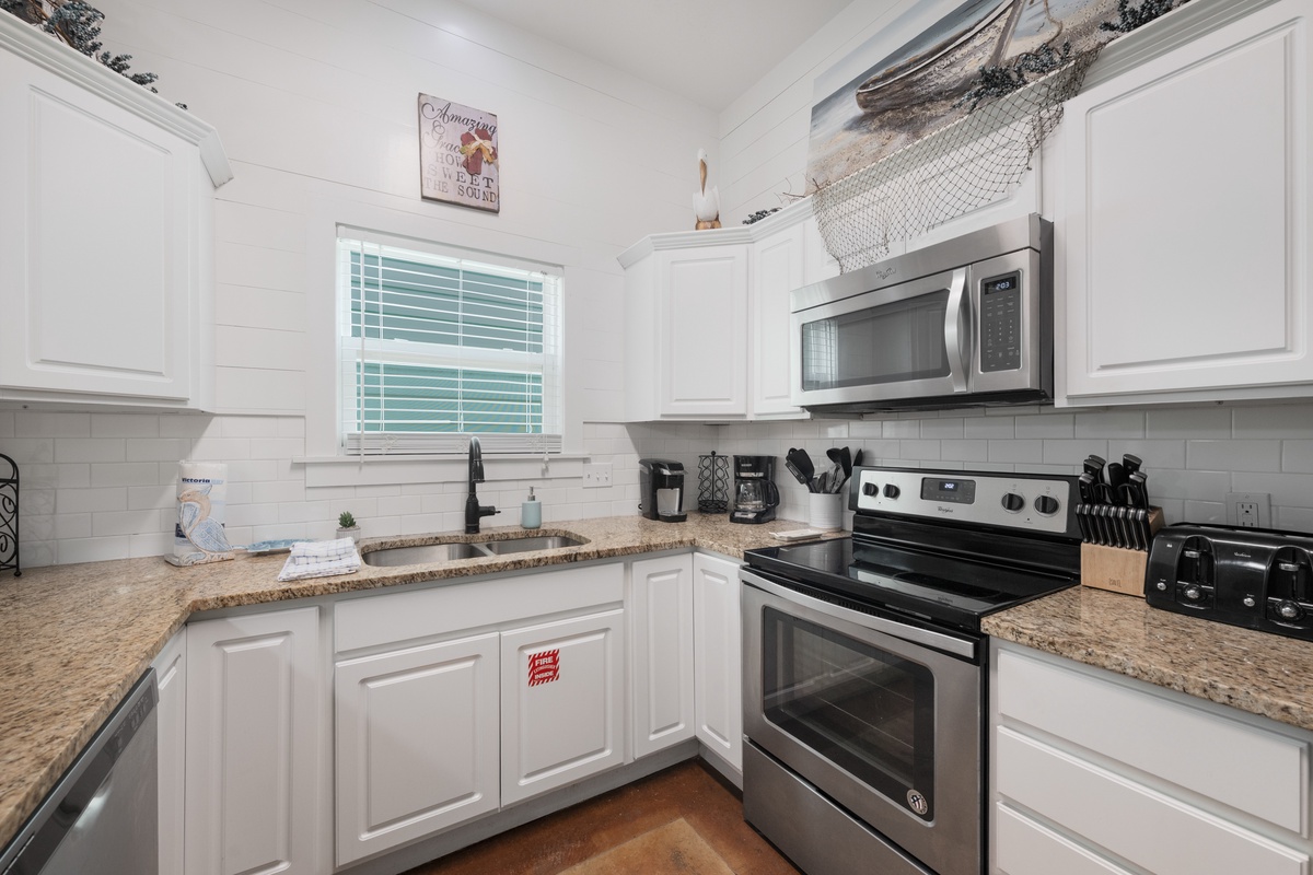 Your fully equipped kitchen features granite countertops, stainless appliances, and coastal charm with nautical netting decor overhead.