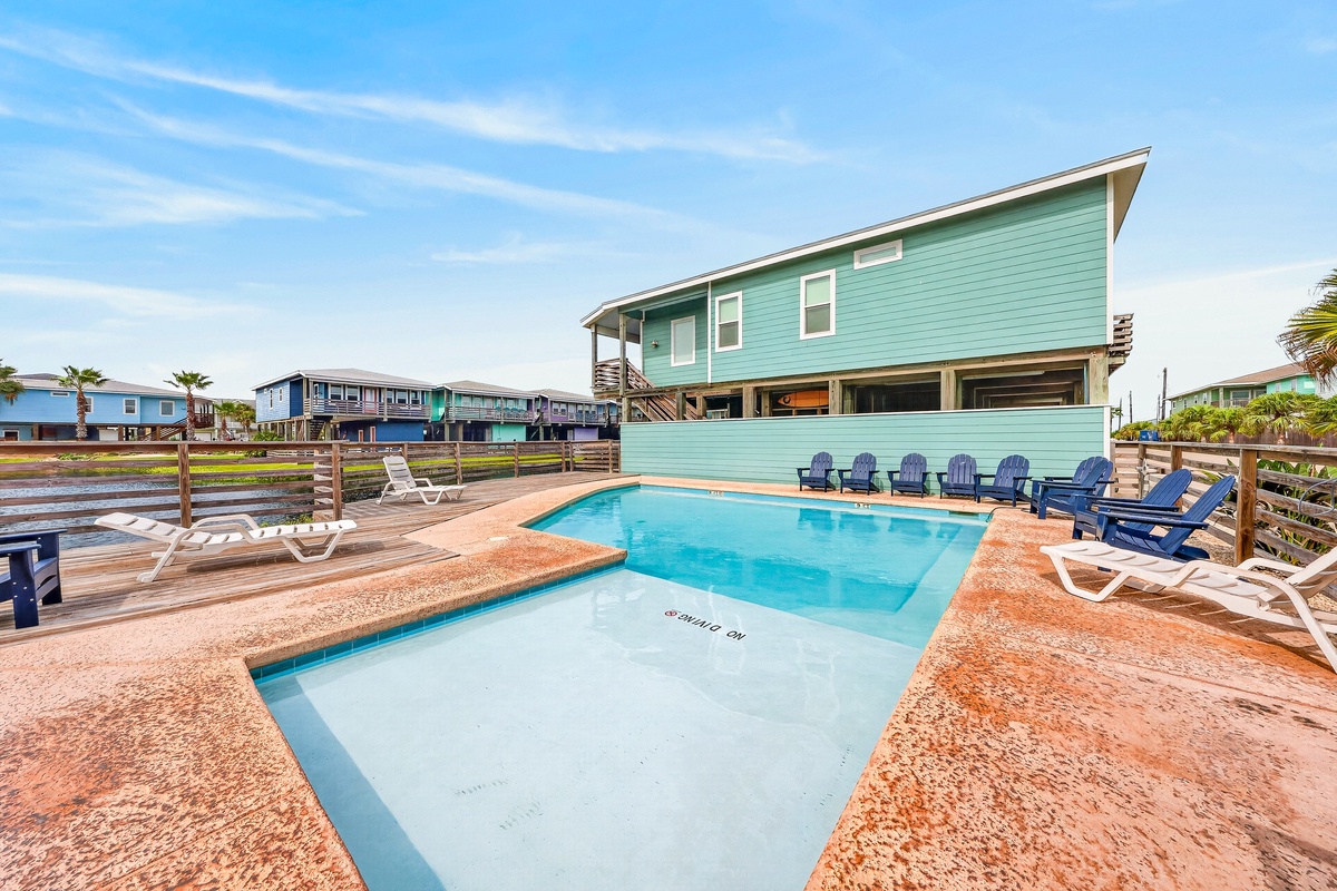 A sparkling pool and sun-soaked deck await you at this bright coastal retreat. Unwind on a lounge chair or gather with loved ones beneath palm trees, all framed by cheerful turquoise charm.