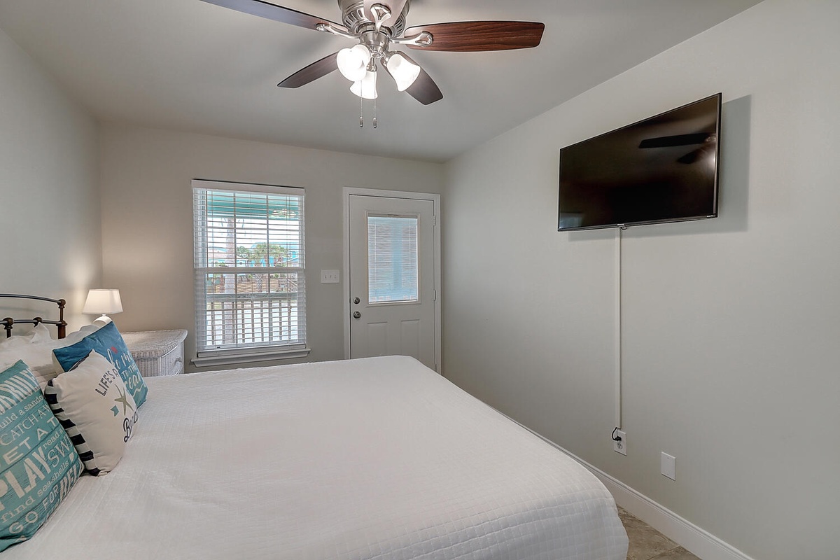 Your peaceful bedroom features a comfortable bed, cooling ceiling fan, and convenient balcony access for fresh air and relaxation.