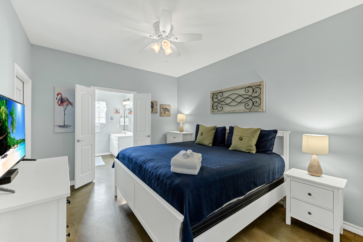 Drift off in your serene bedroom featuring a comfortable bed, gentle ceiling fan, and calming coastal decor that promises restful nights.