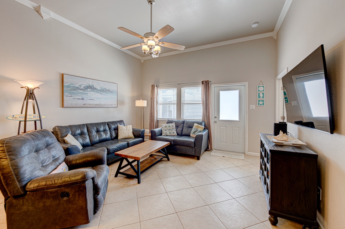 Relax in your spacious living room with plush leather seating, warm lighting, and modern entertainment center for cozy evenings.