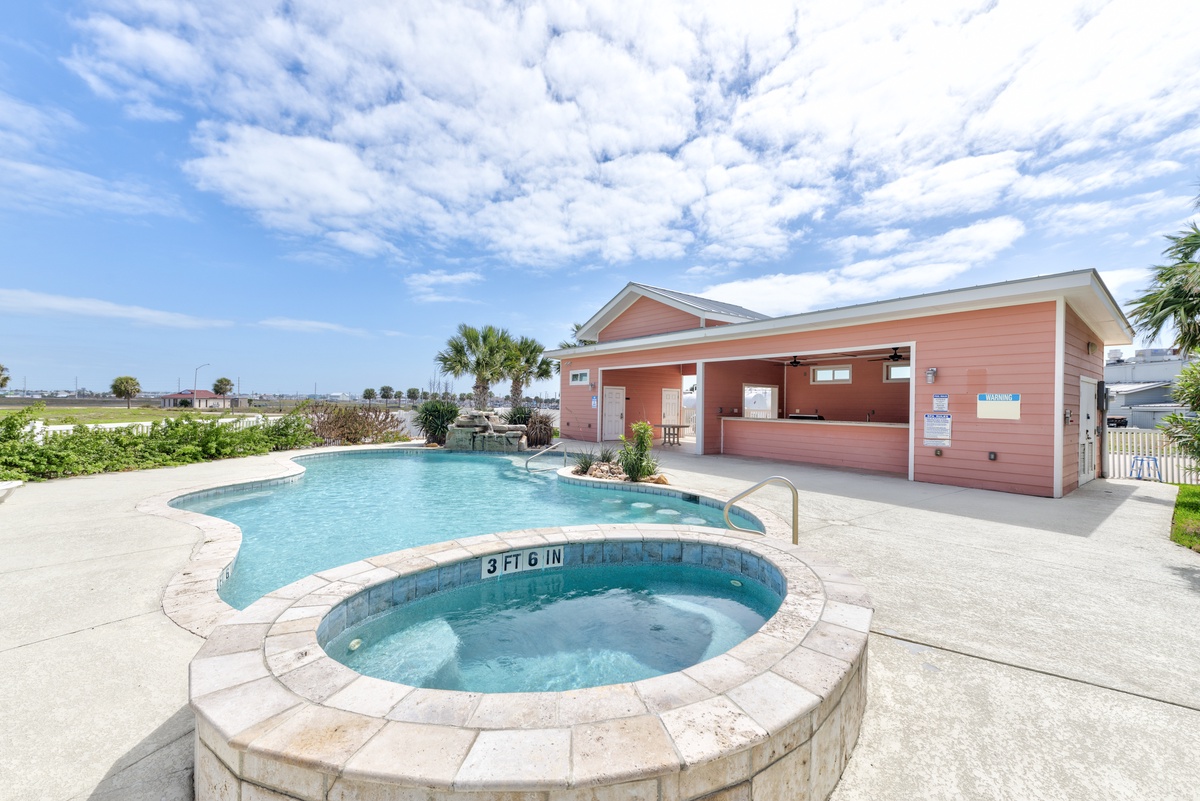 A sparkling pool and hot tub await with a tropical clubhouse backdrop under endless Florida skies.