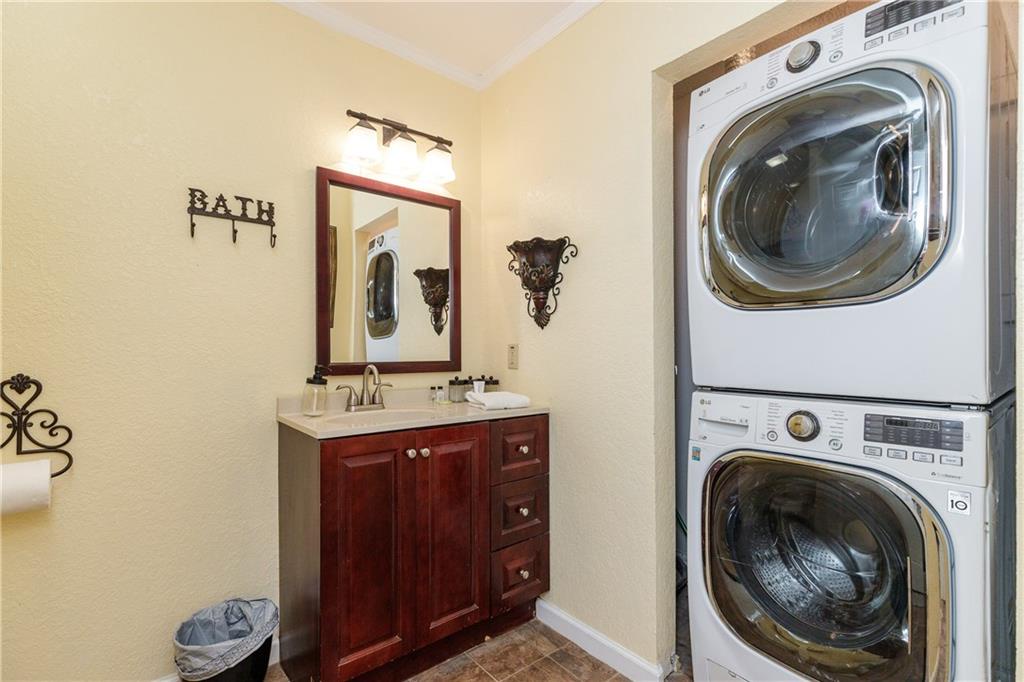 Keep your clothes fresh with modern stacked washer and dryer in this thoughtfully designed space featuring elegant vanity and bathroom access.