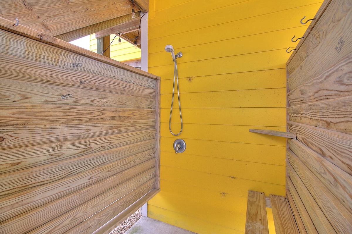 Rinse off in your private outdoor shower, surrounded by natural wood and bright yellow walls that create a cheerful, refreshing space.