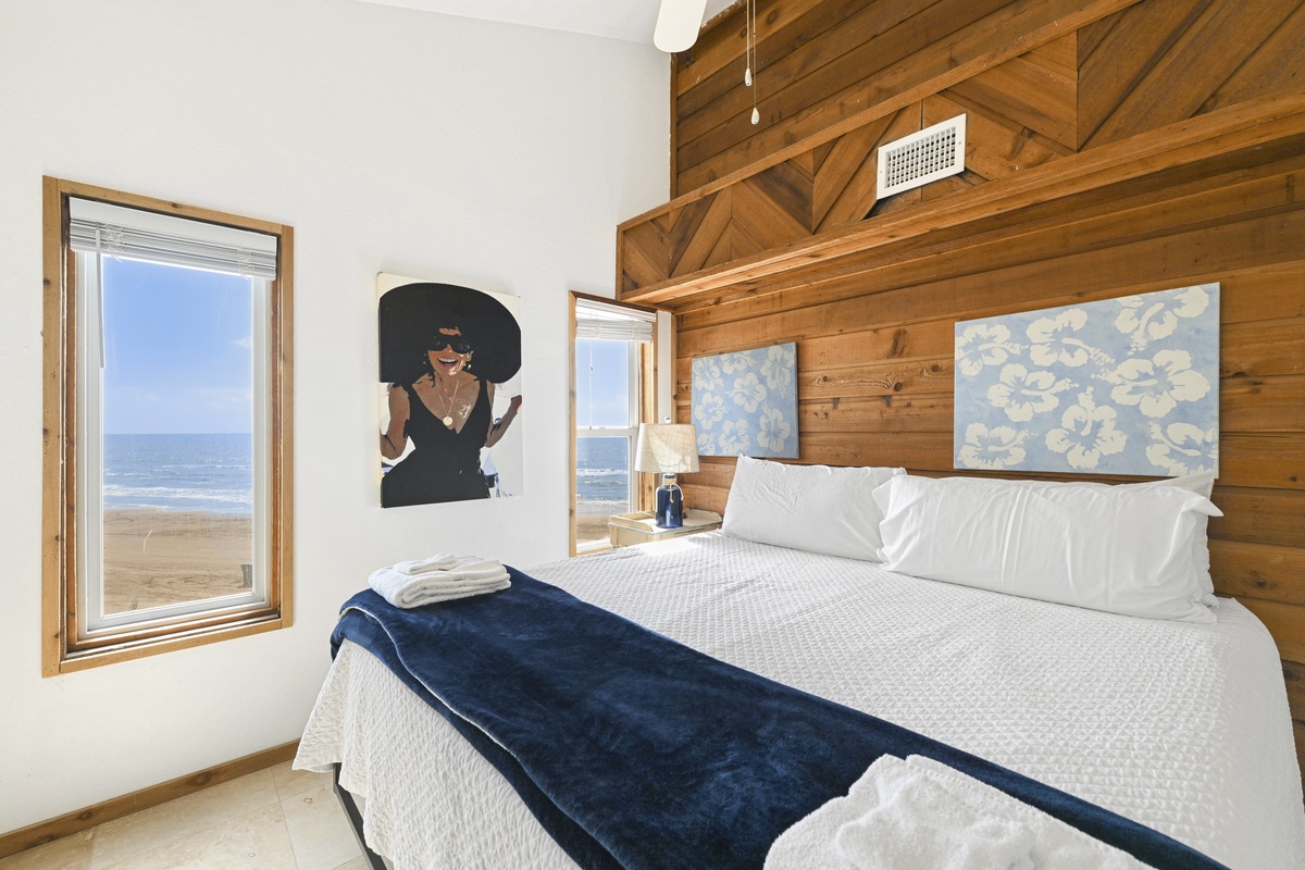 Wake up to stunning ocean views framed by large windows in your serene beachside bedroom, where crisp linens and warm wood accents invite you to unwind.