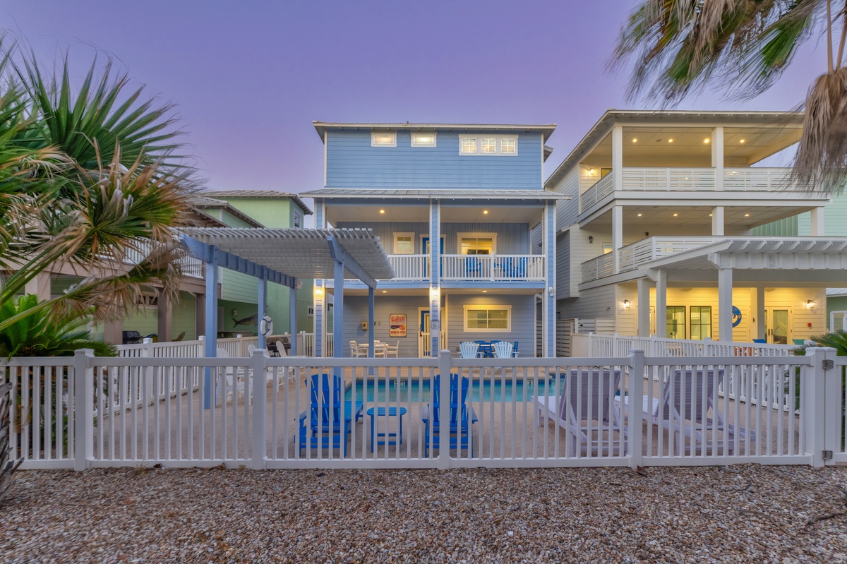 Beautiful beachside vacation rental with private pool surrounded by tropical palms, captured during the magical twilight hour.