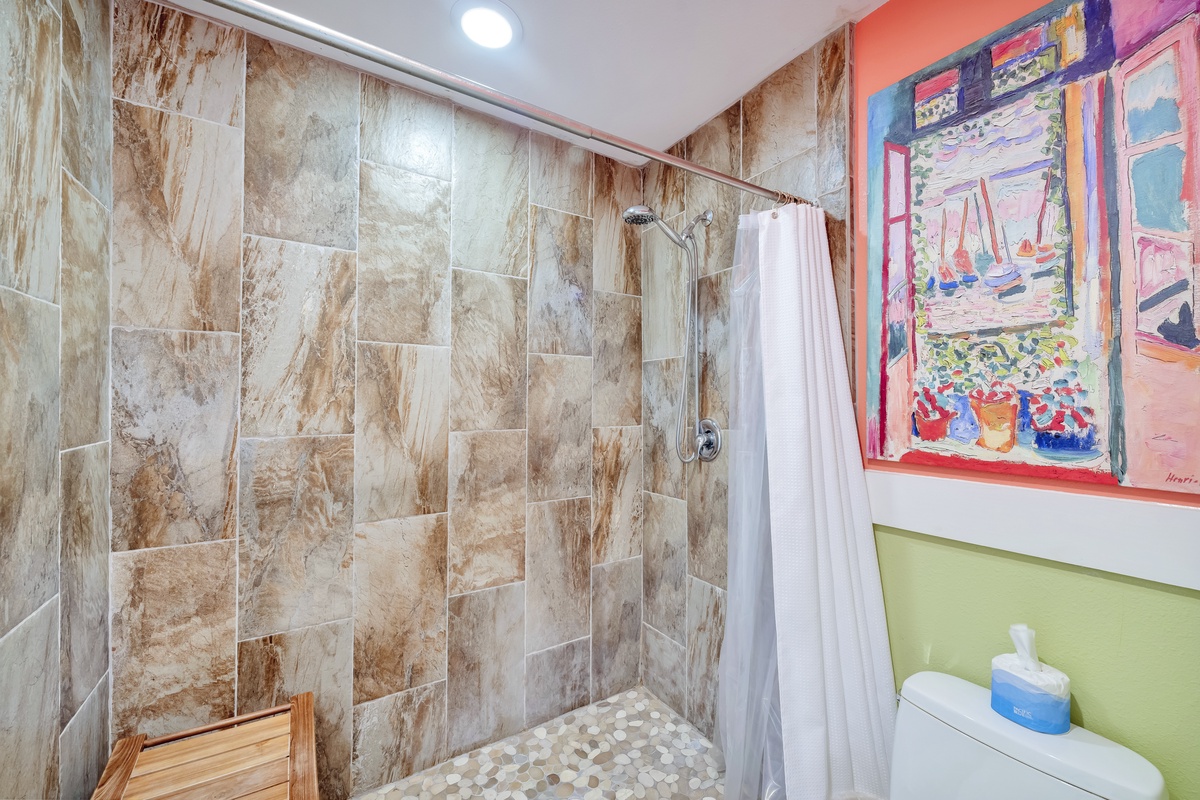 Step into your private marble-tiled shower with artistic flair—vibrant artwork brightens your refreshing bathroom retreat.