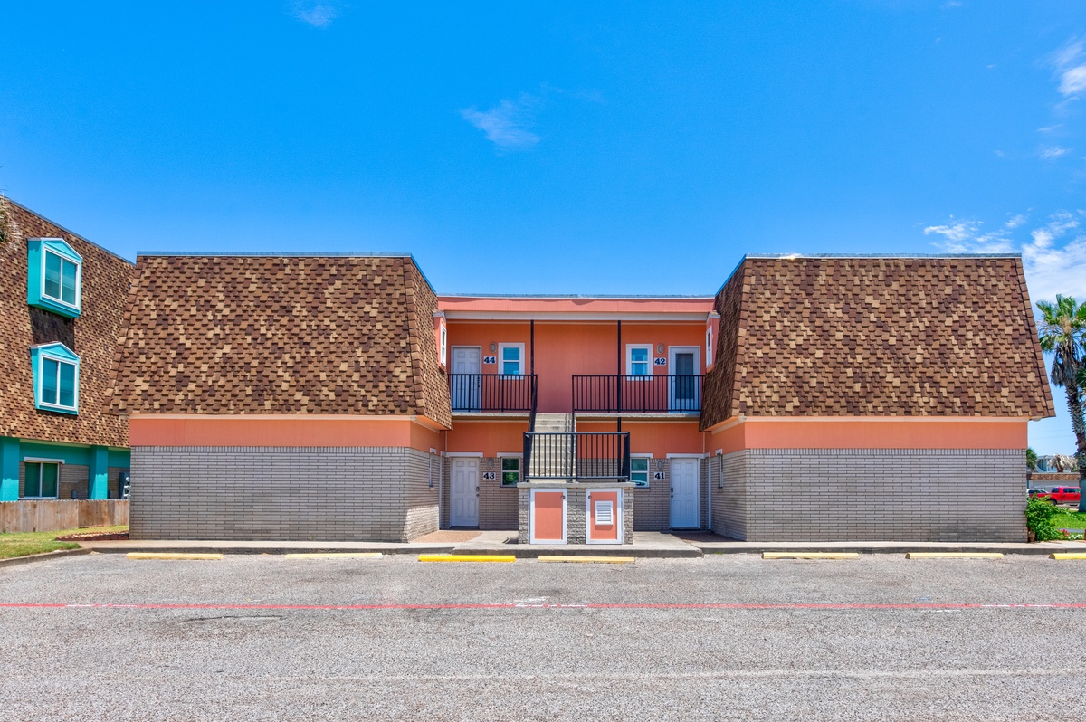 Modern vacation rental building featuring distinctive brick architecture and balconies in a quiet residential area.