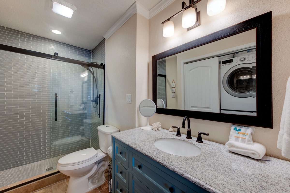 Your elegant bathroom features a spacious glass shower, granite vanity, and convenient in-unit washer/dryer for ultimate comfort during your stay.
