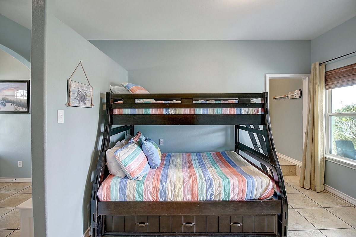 Rest easy in your cheerful bunk room with colorful striped bedding and natural light streaming through.