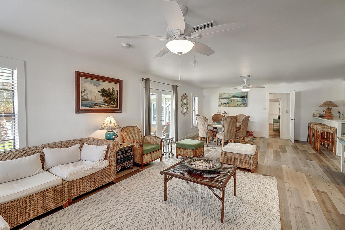 Relax in your bright, airy living space with coastal charm, featuring wicker furniture and warm wood floors that invite barefoot mornings.