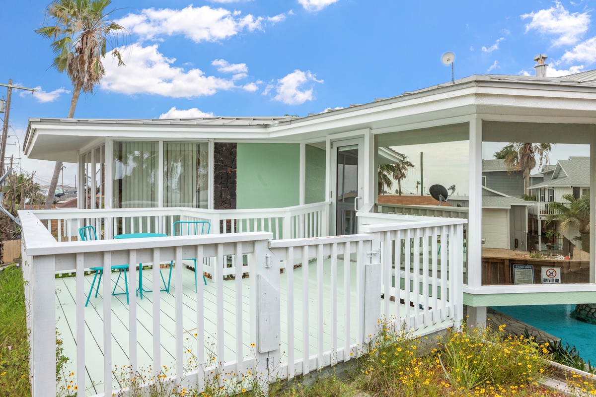 Bright beach house with covered deck and tropical palms creates the perfect coastal retreat for your vacation.