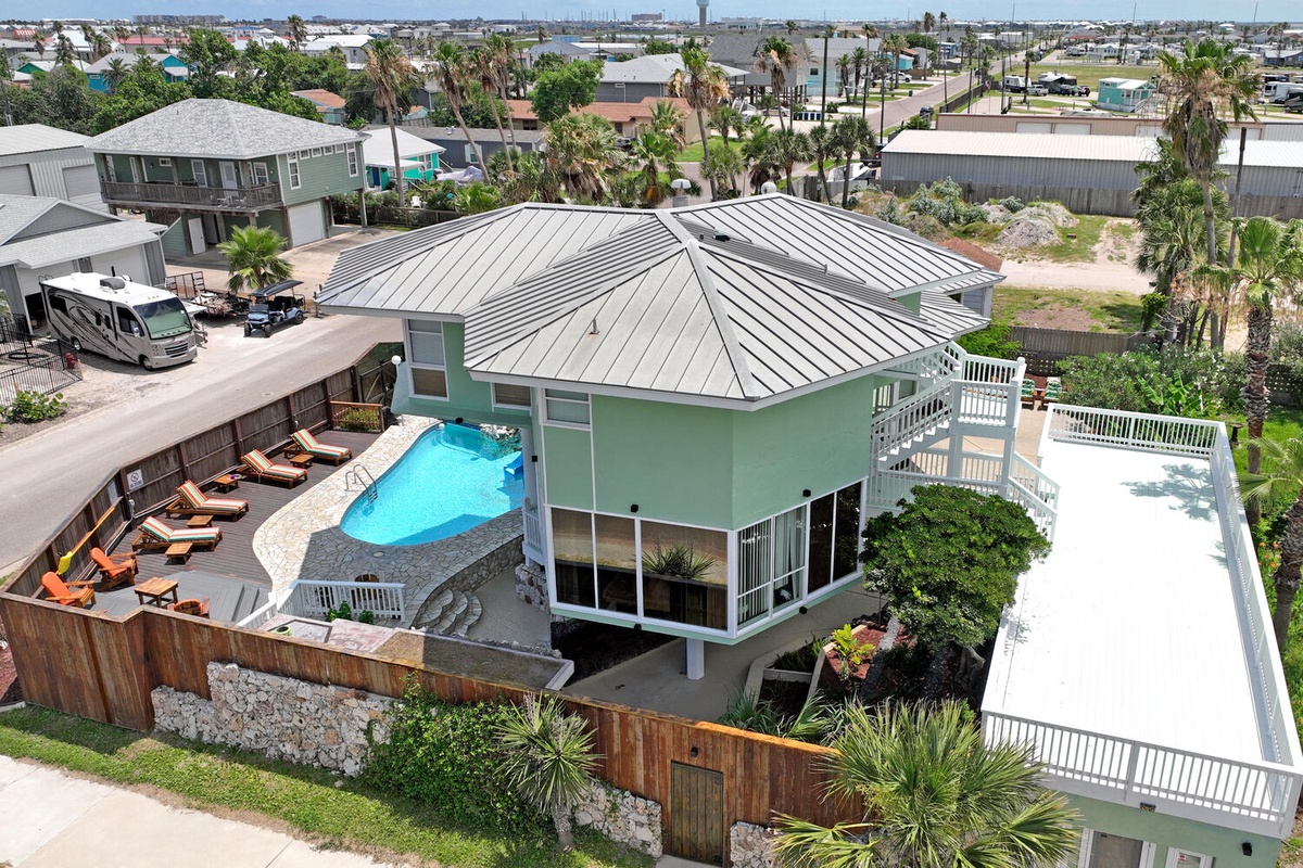 Elevated beach home with private pool, tropical landscaping, and spacious deck areas in a charming coastal neighborhood setting.