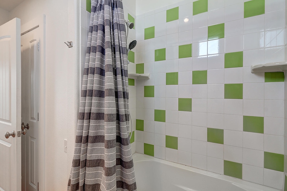 Refresh in your private bathroom featuring vibrant green tile accents and a spacious shower.