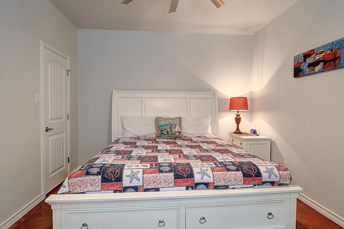 Drift into peaceful sleep in your cozy bedroom, wrapped in charming coastal quilts beneath the warm glow of bedside lighting.