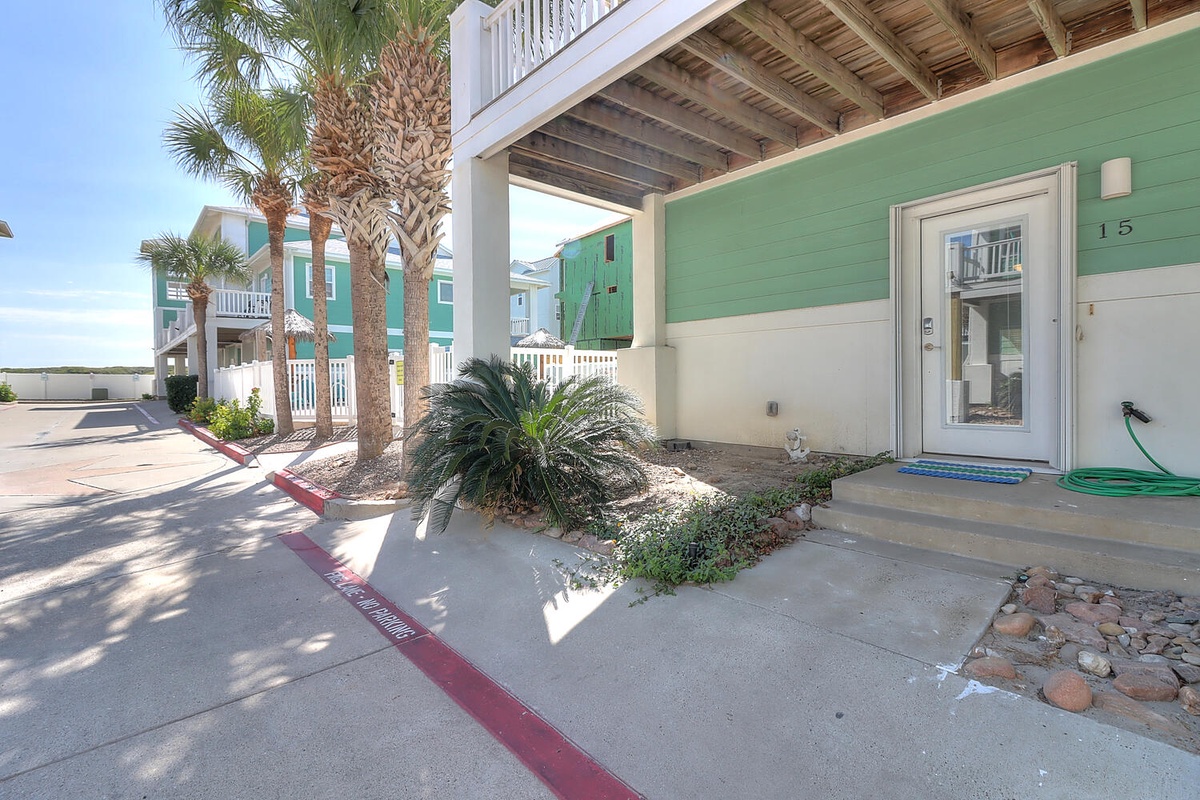 Colorful beachside property entrance with tropical palm trees and coastal architecture creating a welcoming vacation atmosphere.