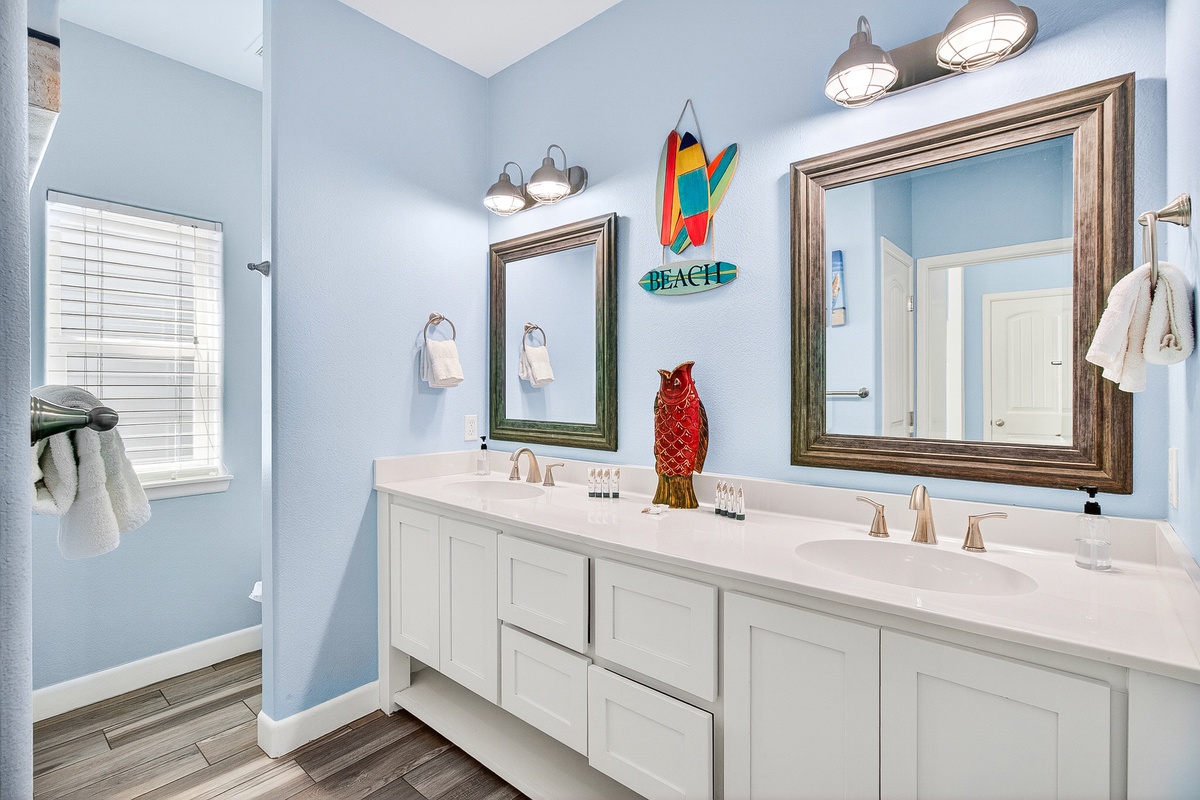 Refresh in your coastal-inspired bathroom featuring dual vanities, tropical decor, and beach vibes that make every morning feel like vacation.