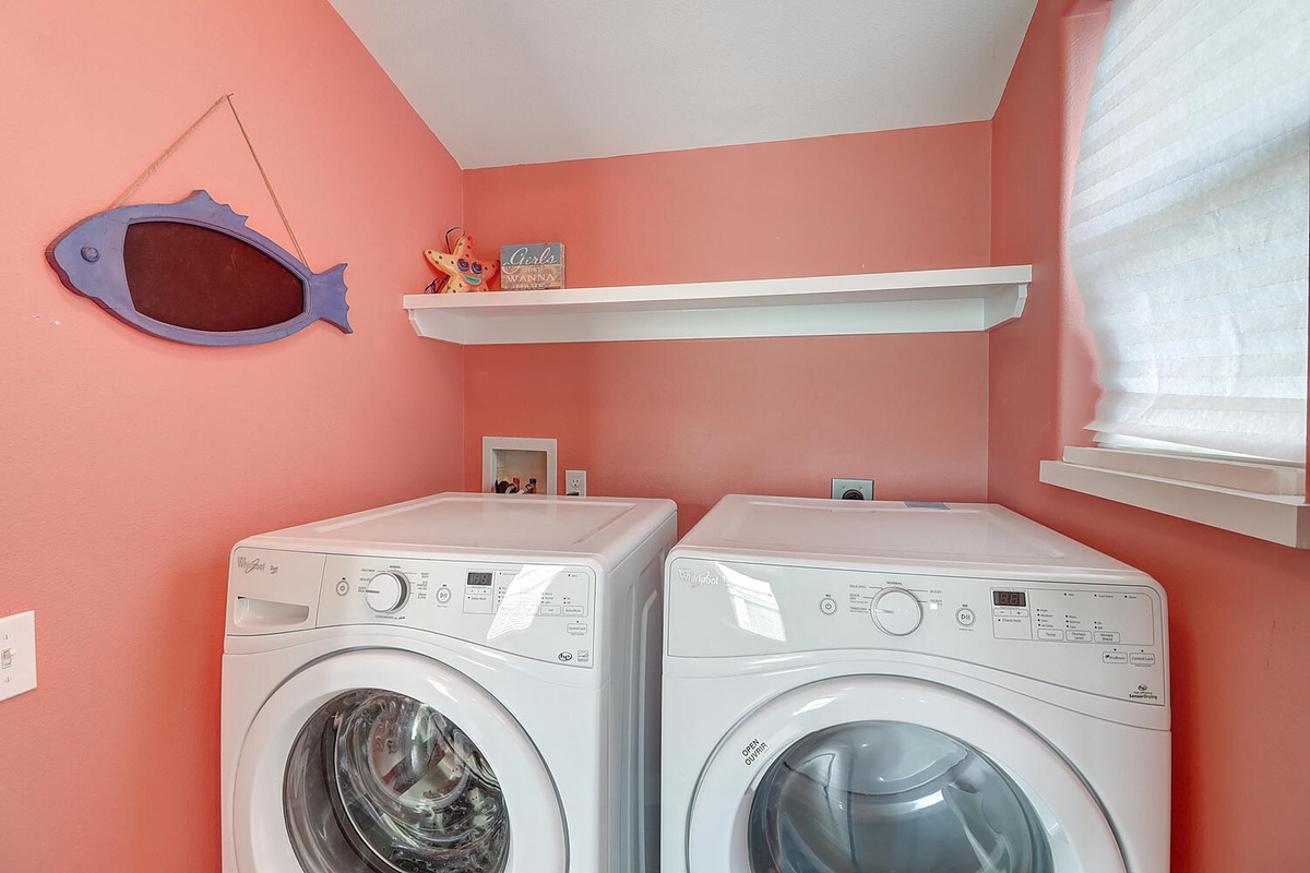 Your laundry stays fresh in this cheerful coral-walled space with full-size washer and dryer, complete with handy shelving for supplies.