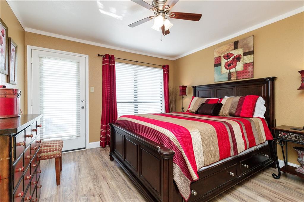 Relax in your cozy bedroom with plush striped bedding, warm golden walls, and convenient patio access for morning coffee or evening breezes.