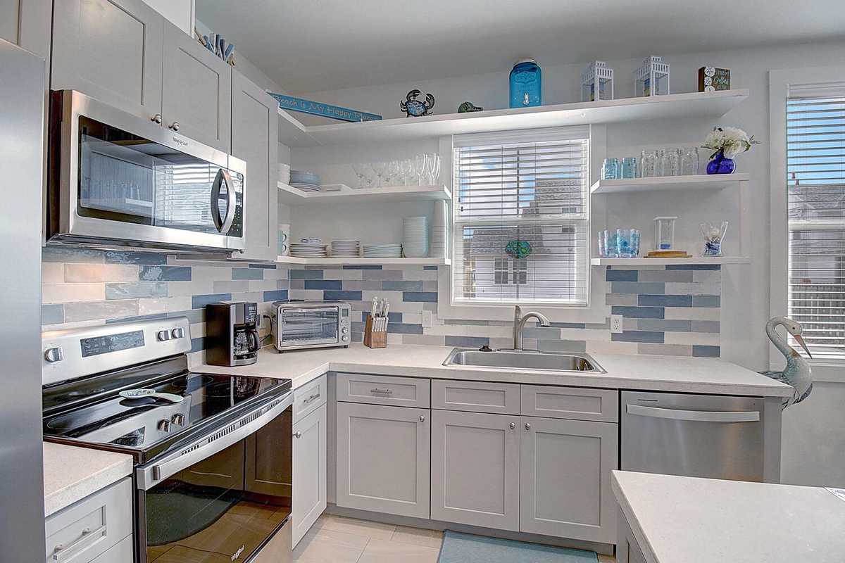 Your bright, fully equipped kitchen features modern appliances and coastal-inspired tile backsplash for memorable meal preparation.