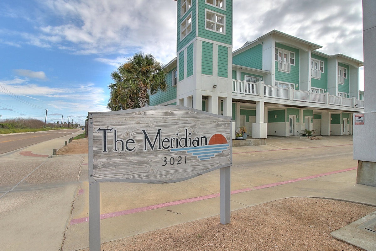 The Meridian property sign welcomes guests to this coastal destination with colorful beach houses and palm trees.