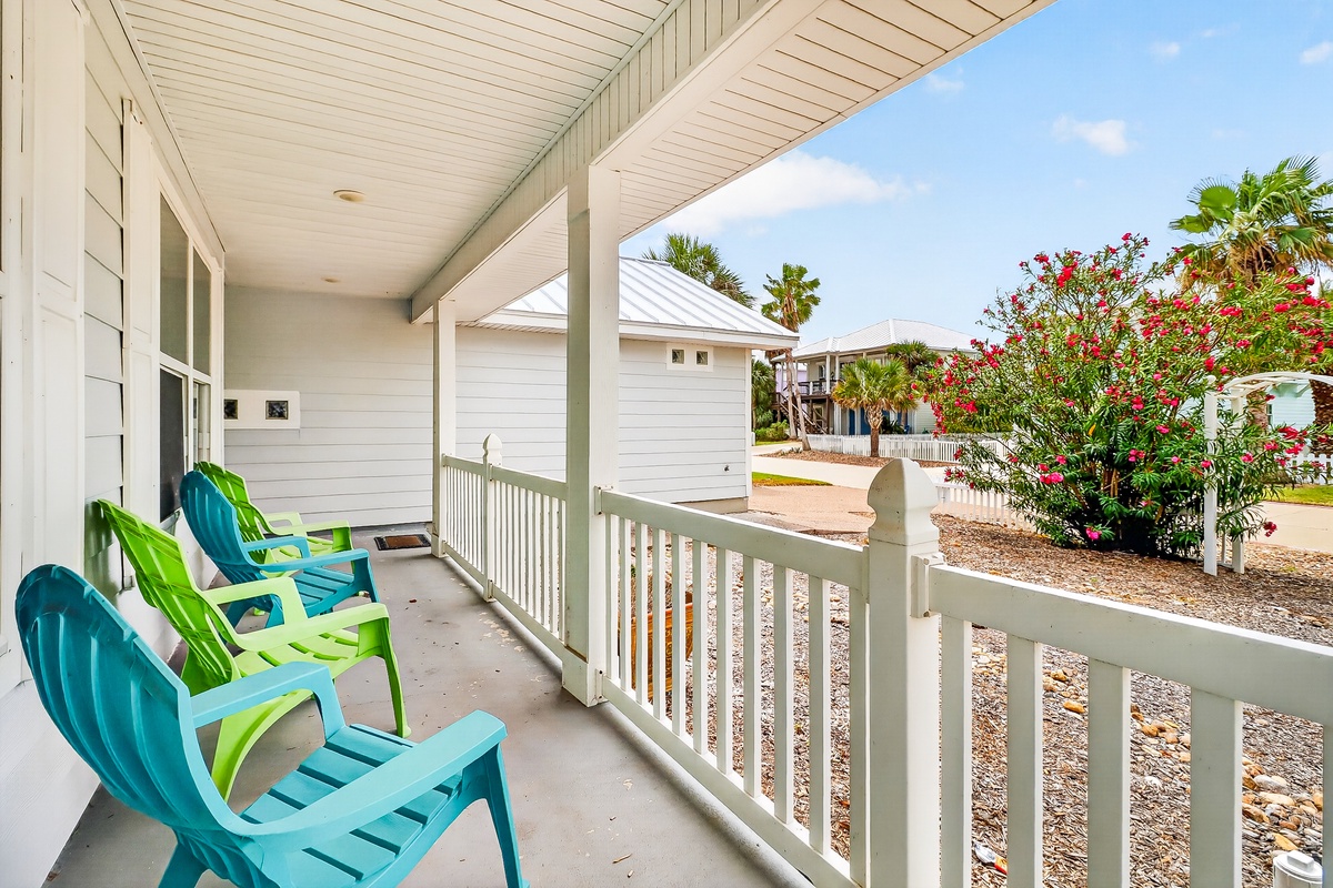 Unwind in your colorful beach chairs on this covered porch, where tropical blooms frame peaceful neighborhood views.