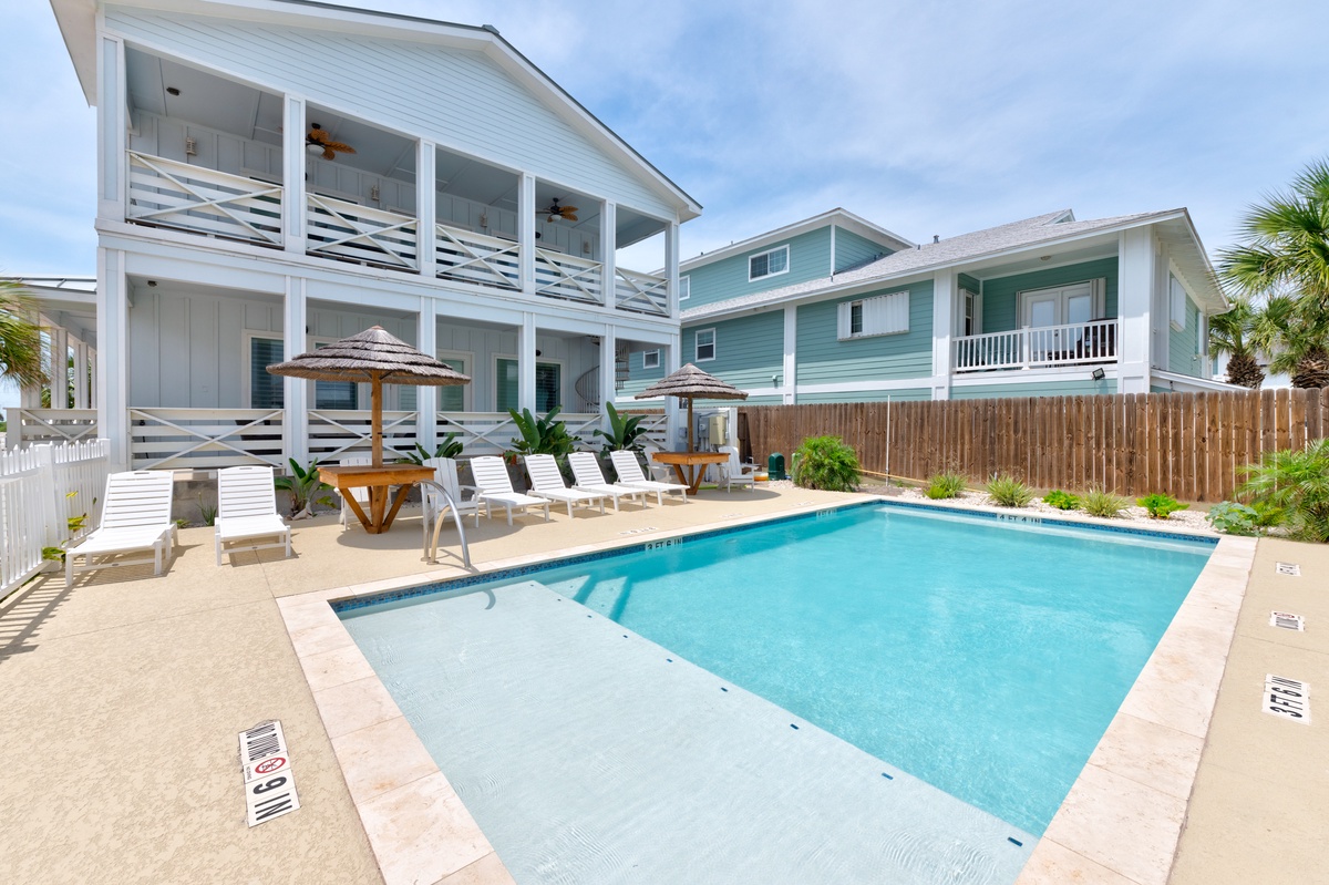 Dive into your private pool paradise, surrounded by tropical palms and sun loungers for the perfect beach getaway.