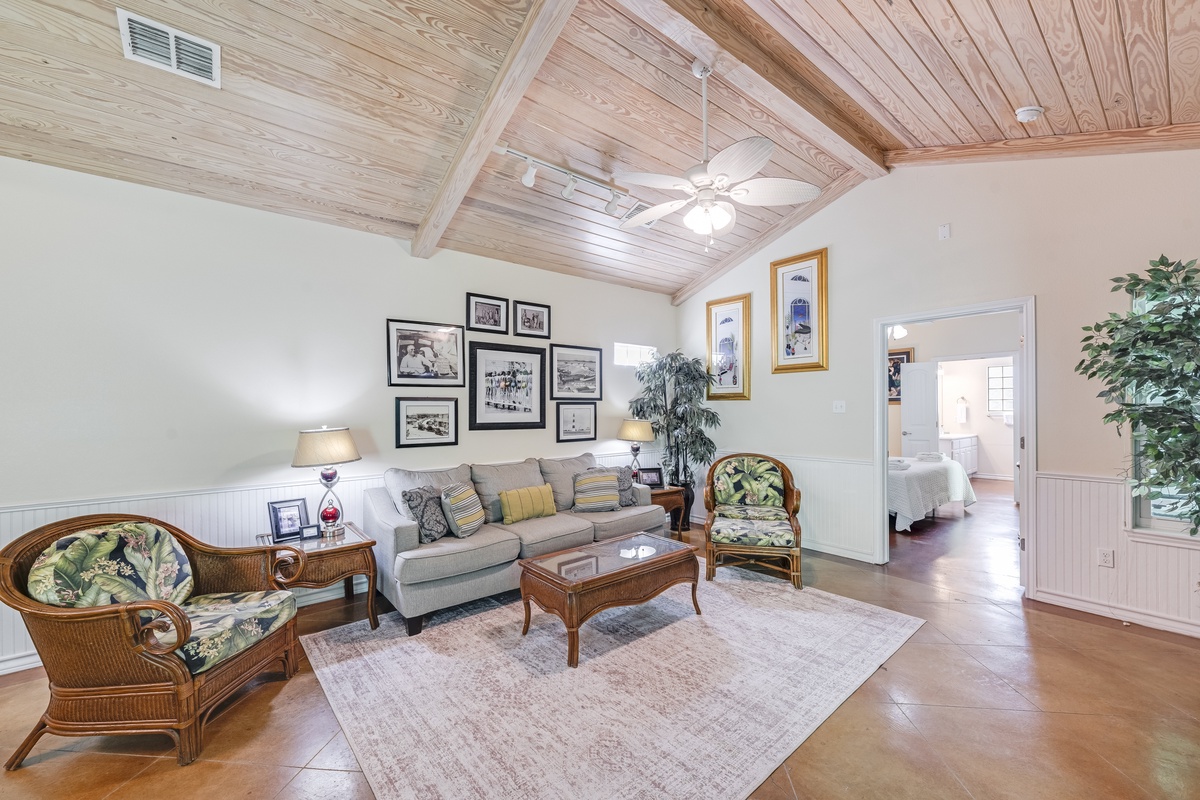 Relax in your charming living room with exposed wood beam ceilings, tropical-style seating, and thoughtful decor that creates a warm, welcoming atmosphere.