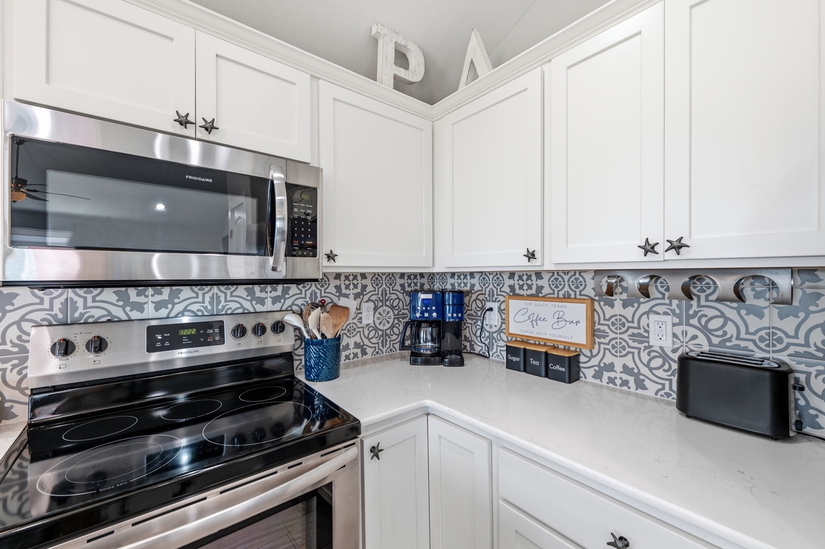 Your bright, fully equipped kitchen features crisp white cabinetry, modern stainless appliances, and charming patterned tile backsplash. Everything you need for easy meal prep and your morning coffee awaits.