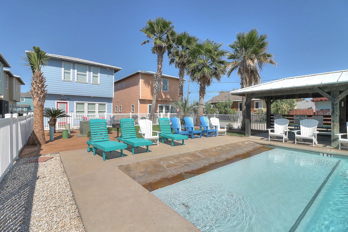 Dive into your private pool oasis, where colorful loungers and swaying palms create the perfect coastal retreat for sunny days.