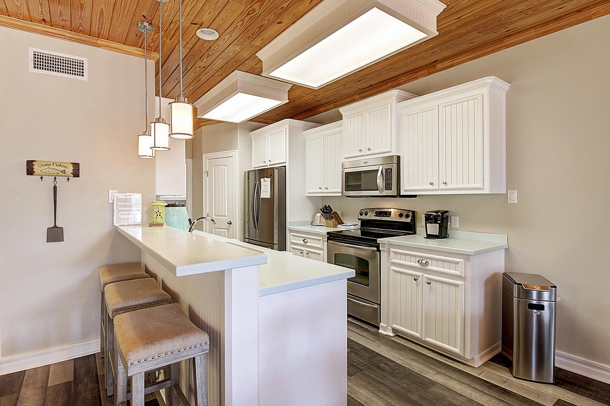 Your gourmet kitchen awaits with gleaming appliances, granite counters, and a charming breakfast bar under stunning wood beam ceilings.