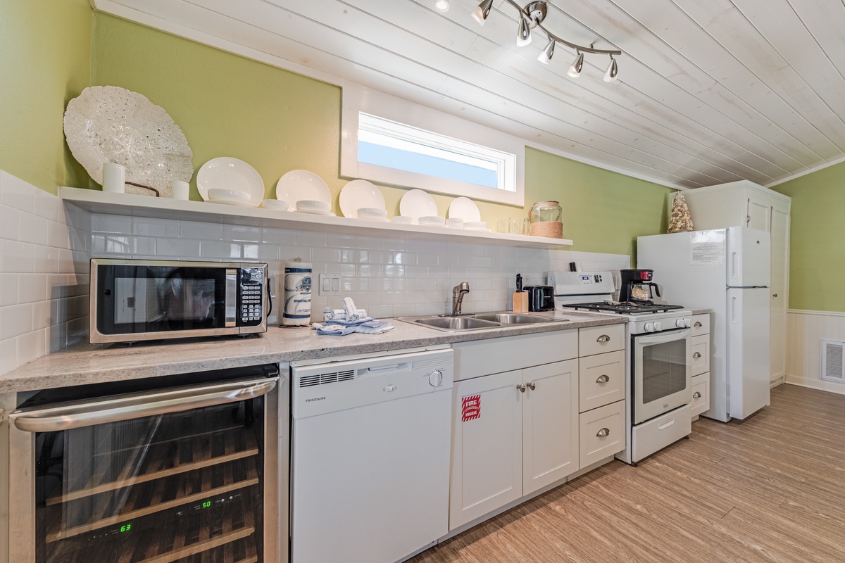 Your fully equipped kitchen features modern appliances and charming green walls under vaulted ceilings with warm wood beams.