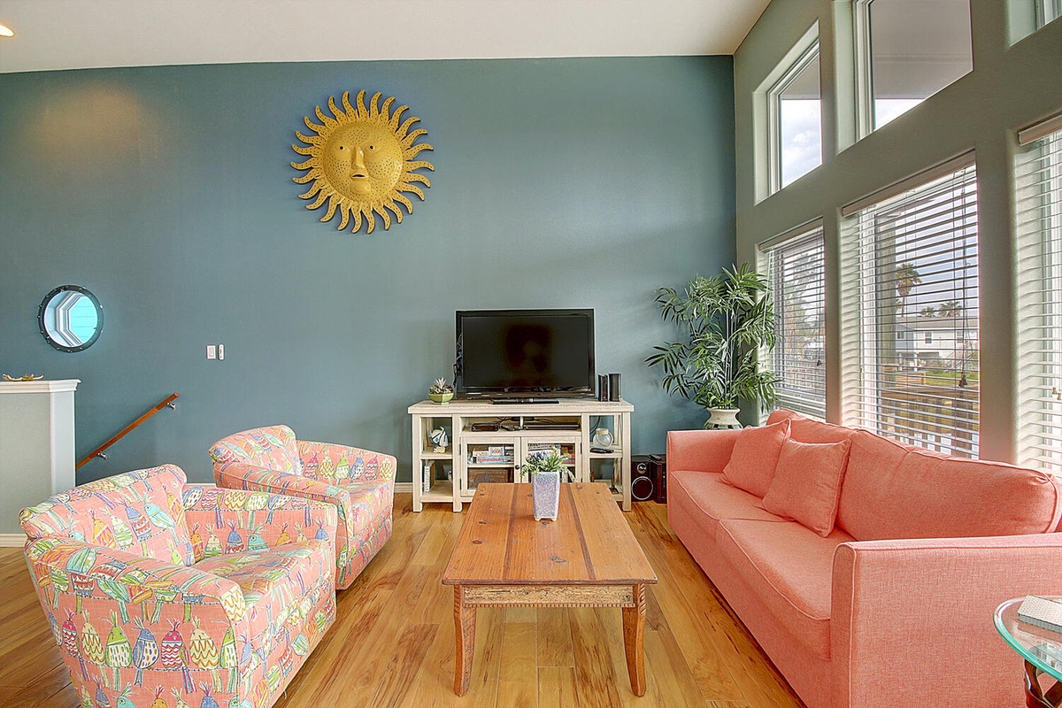 Relax in your bright living room where colorful seating meets calming blue walls, perfect for movie nights.