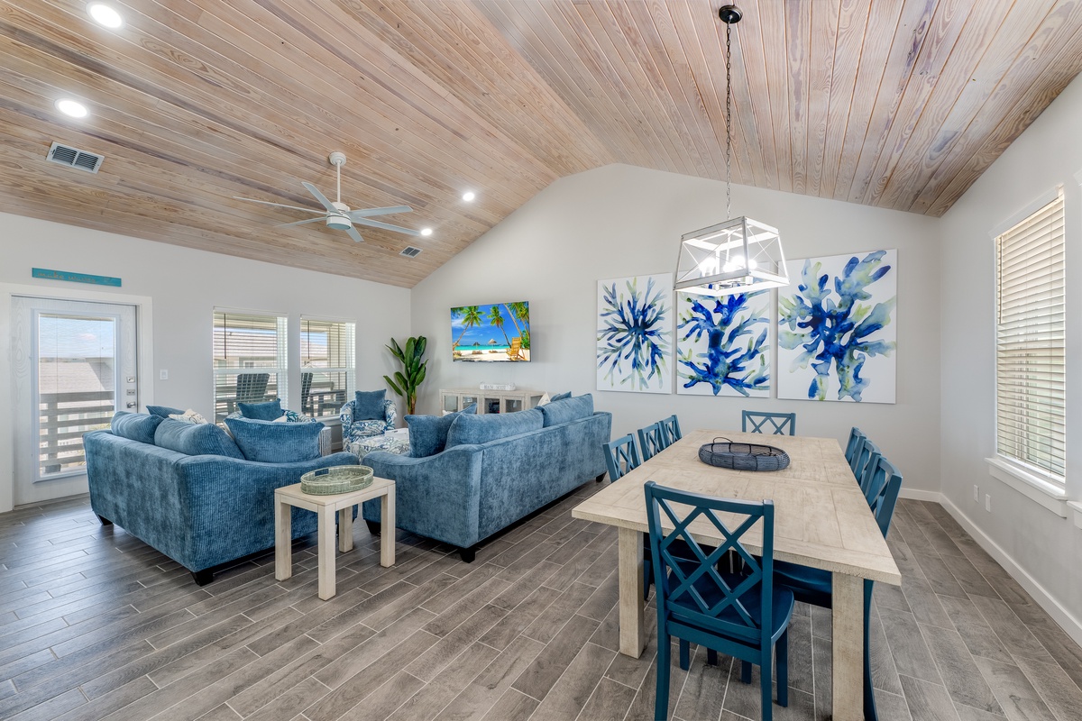 Relax in your coastal-inspired living space with plush blue seating and ocean-themed art. The stunning wood ceiling and open layout create perfect gathering spaces.