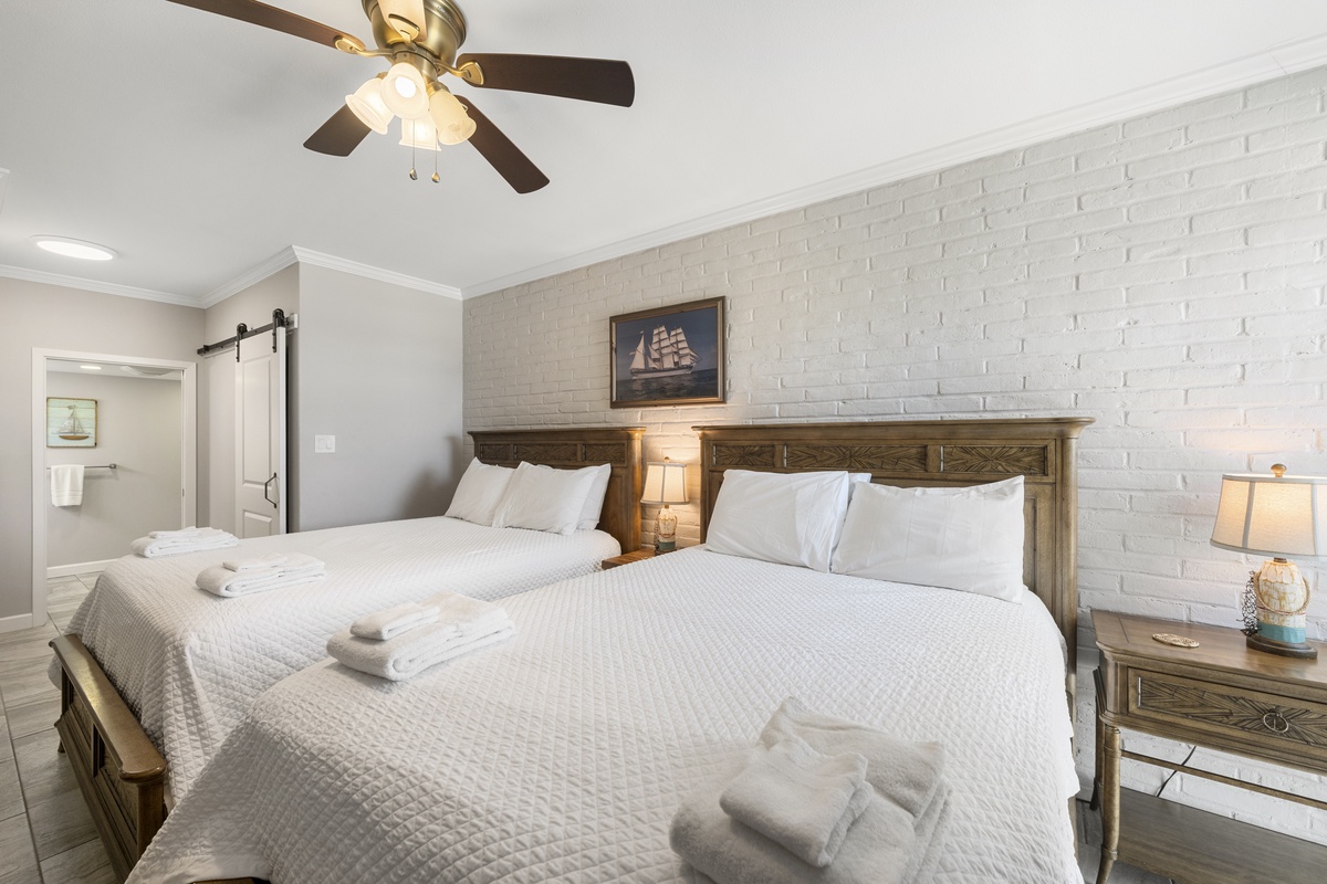 Drift off in your charming nautical bedroom with cozy twin beds, rustic wood headboards, and a gentle ceiling fan for perfect comfort.