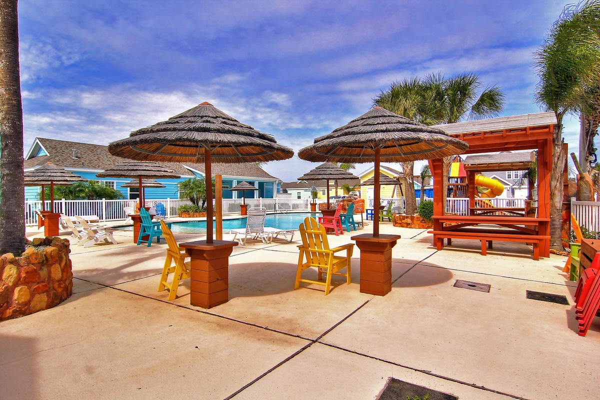Relax under tropical umbrellas by your private pool, where colorful chairs and swaying palms create the perfect Caribbean escape.