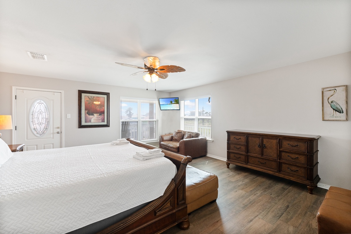 Relax in your spacious bedroom featuring a king bed, cozy seating area, and tropical ceiling fan for ultimate comfort.