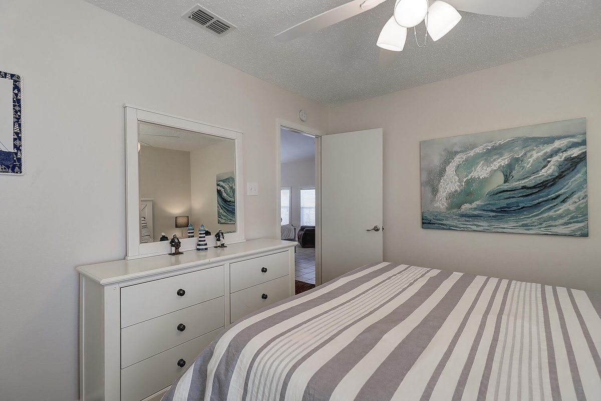 Your peaceful bedroom features coastal artwork and crisp linens, with a ceiling fan to keep you comfortable during warm nights.