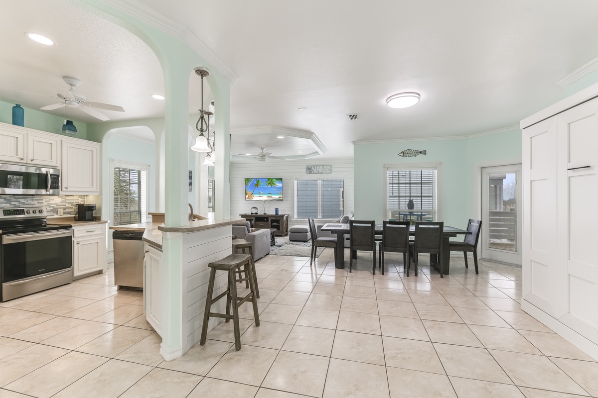 Your open-concept kitchen and dining area flows seamlessly with modern appliances, breakfast bar seating, and coastal-inspired decor for memorable meals together.