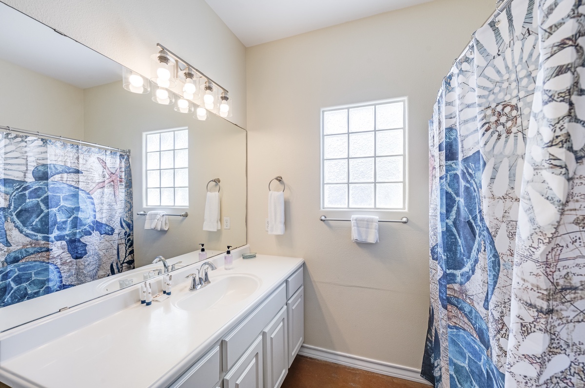 Refresh in your private bathroom featuring ocean-themed décor, bright vanity lighting, and nautical charm that makes every morning feel like a coastal escape.